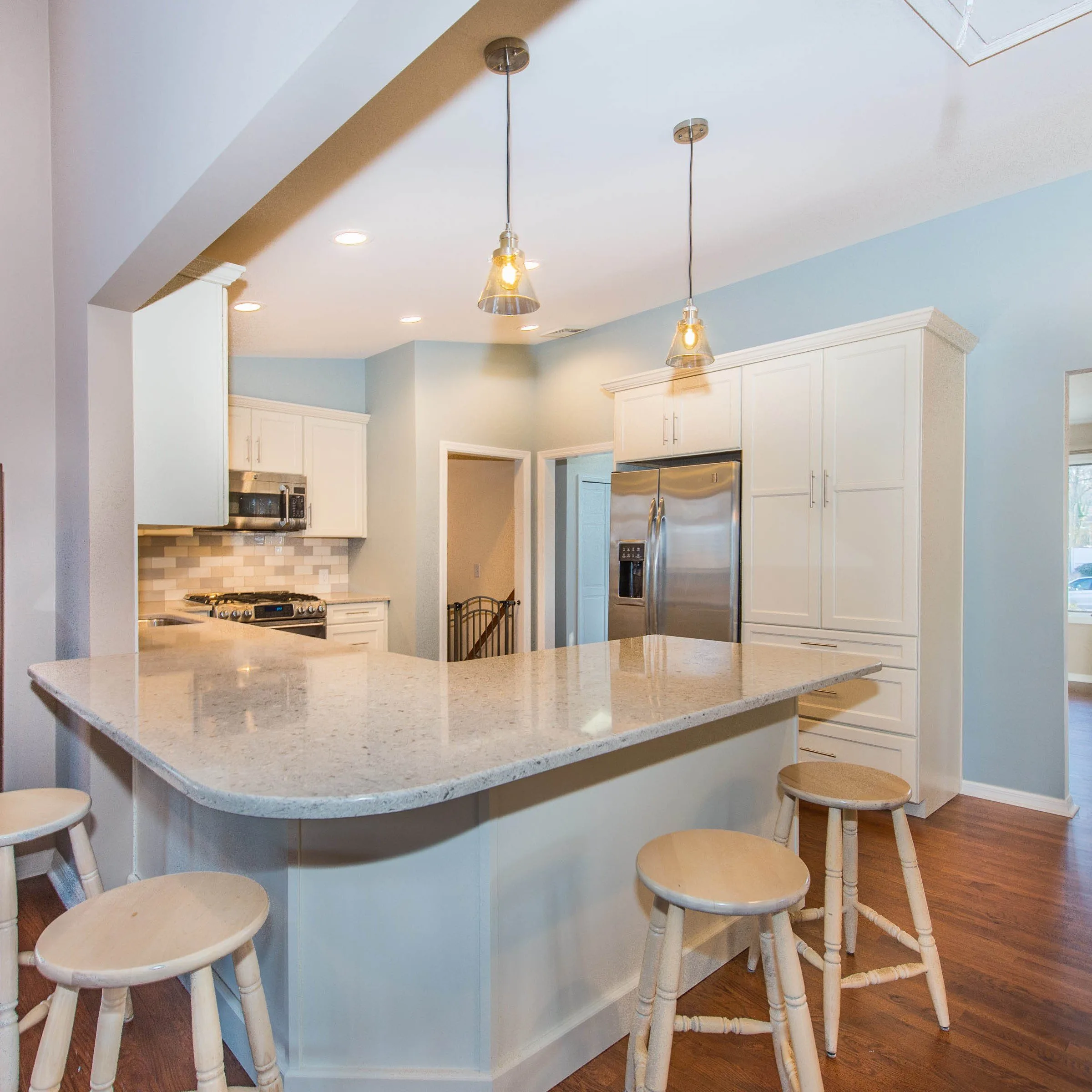 A contemporary remodeled kitchen in Bradford, complete with a central island and stools, perfect for dining and socializing.