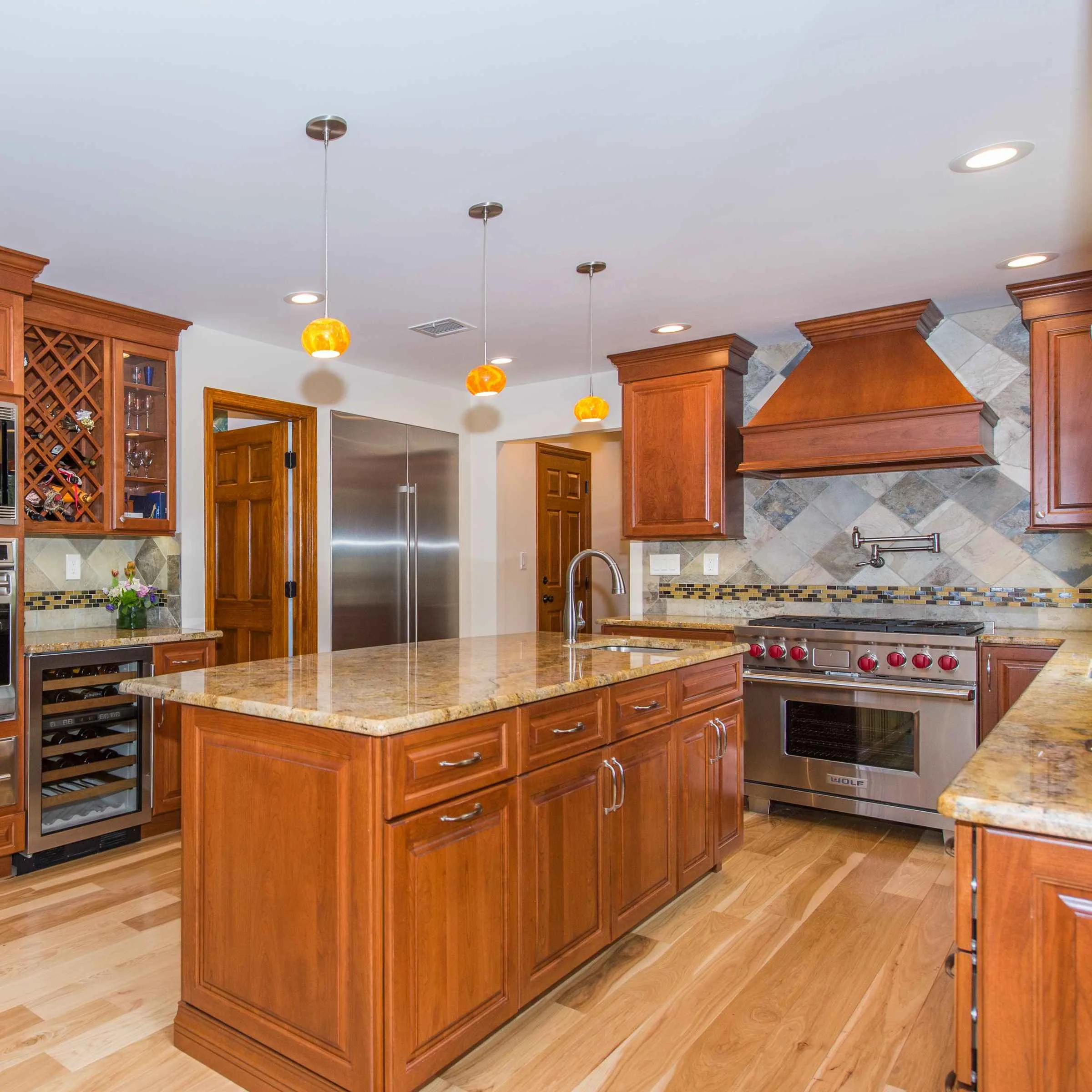 Spacious kitchen with wooden cabinets, a large island featuring a granite countertop, stainless steel appliances, and elegant pendant lighting—perfect for those considering kitchen remodeling in Bradford.